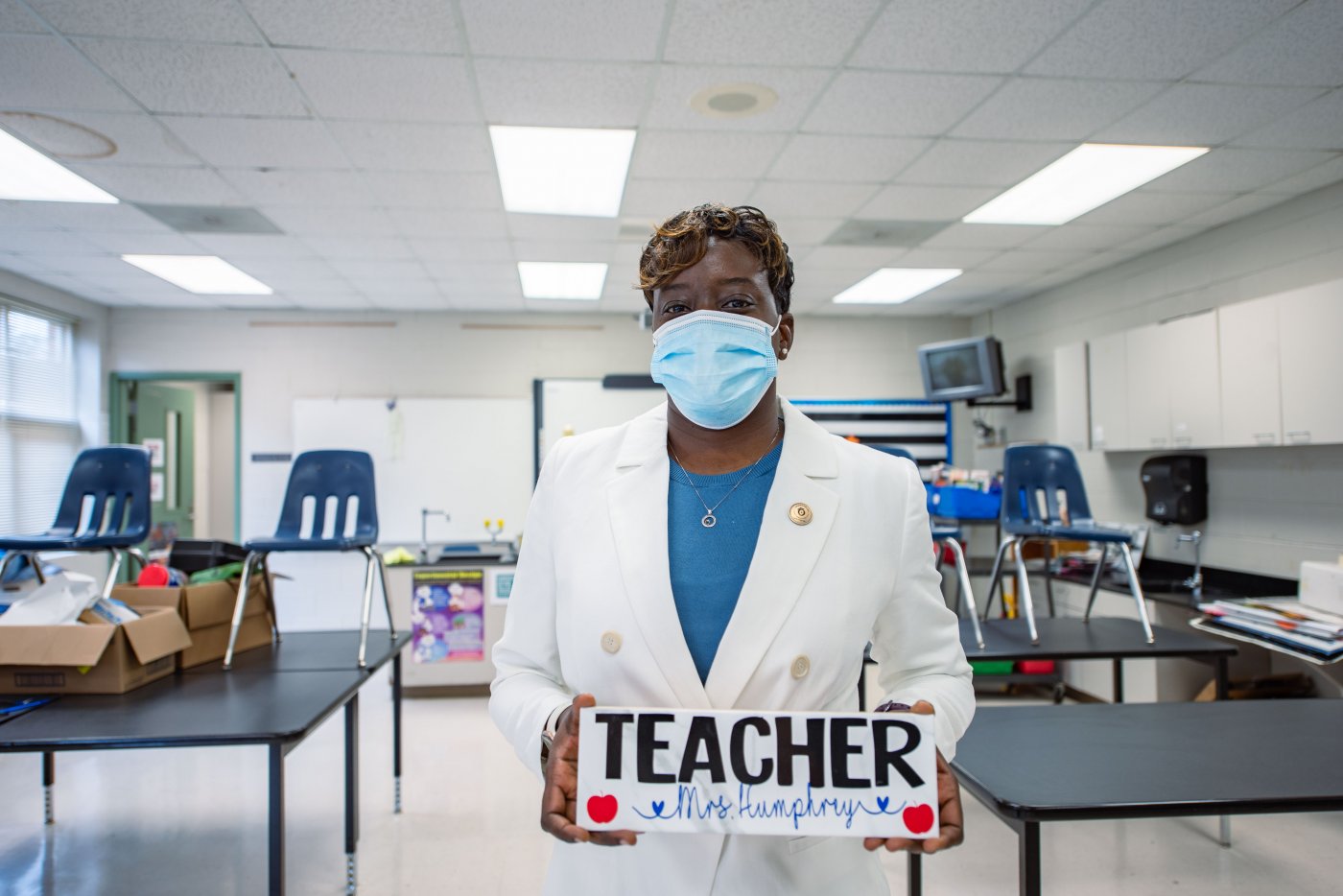 Teacher stands in front of the classroom holding her nameplate